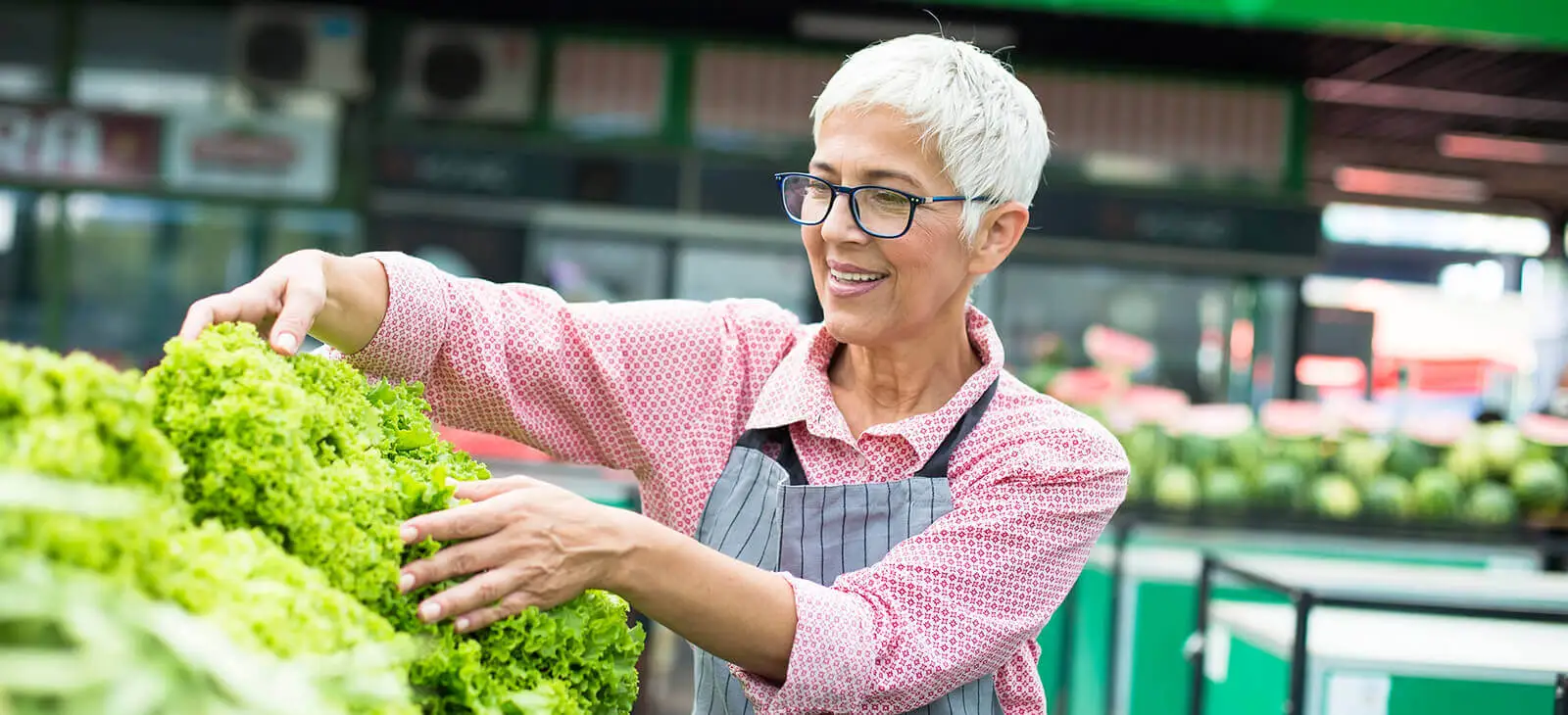 Senior women sells lettuce on marketplace