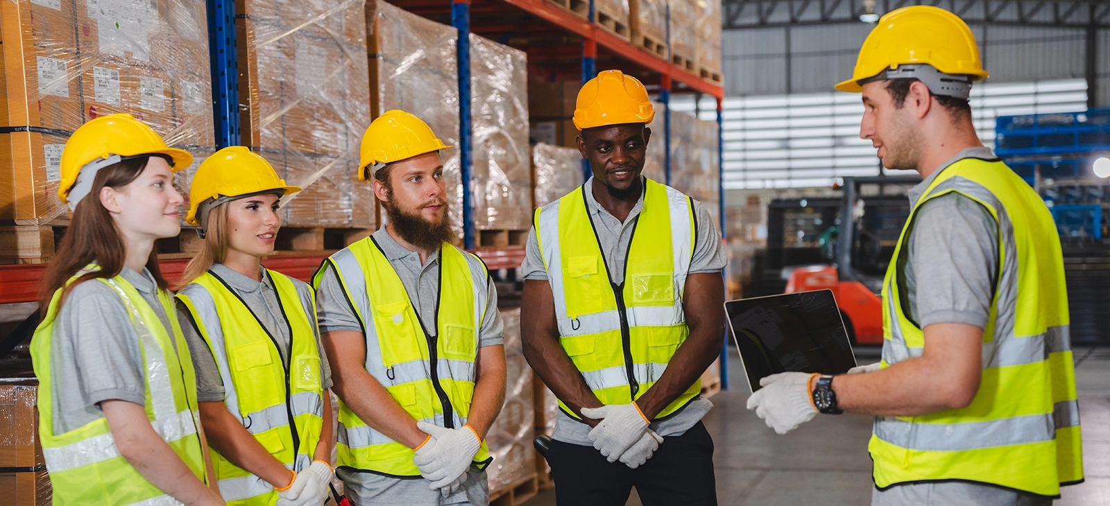 Warehouse team in safety vests and helmets receiving instructions
